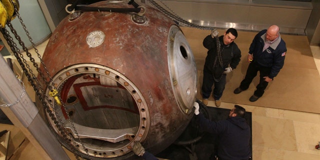 Workers move the Vostok 3KA-2 space capsule into place for display at Sotheby's in New York.