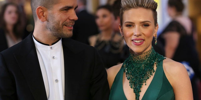 Actress Scarlett Johansson wears a Versace dress as she and then-husband Romain Dauriac arrive at the 87th Academy Awards in Hollywood, California February 22, 2015.