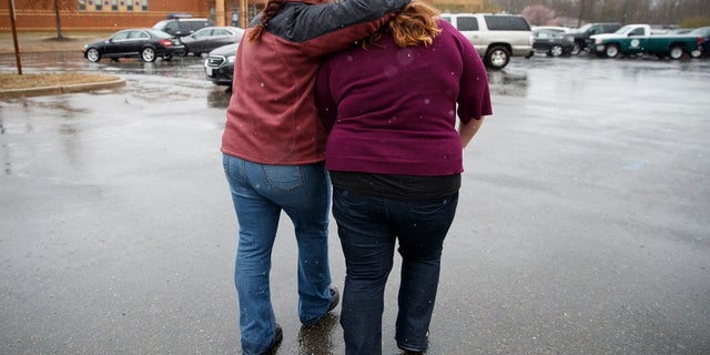 A mother comforts her daughter after a school shooting at Great Mills High School on Tuesday, March 20, 2018.