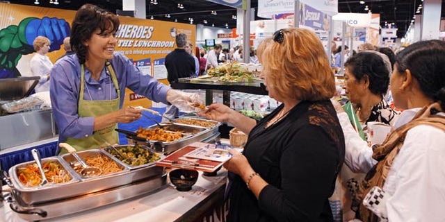 July 17, 2012: Diane Wagner, with Schwan Food Co., hands out samples at a booth during the School Nutrition Association conference in Denver.