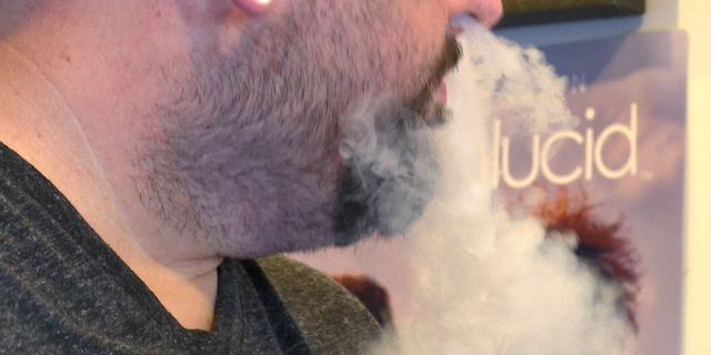 The general manager of Vape 911 in Atlanta vapes while describing different products to customers in the store.