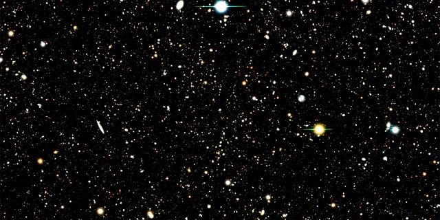 This image shows the results of a deep field survey by the Subaru Telescope. A new analysis used a Subaru deep field image to identify the location of nearly 1,300 distant galaxies. The analysis then combined the UV radiation from those galaxies to learn about their composition. A few bright supernovas can also be seen in the image.