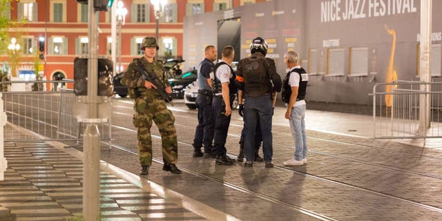 Police officers and a soldier stand by the sealed off area of an attack in Nice, France in wake of a deadly terrorist attack that killed 84 people including 2 American tourists.