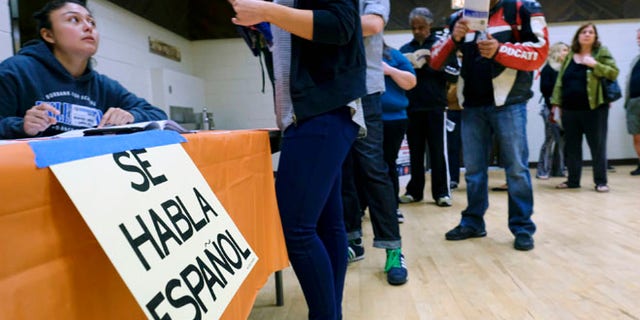 A sign that reads "Spanish is Spoken Here" hangs as voters check in at the North Hollywood Amelia Earhart Regional Library polling station in Los Angeles on Tuesday, Nov. 8, 2016. (AP Photo/Richard Vogel)