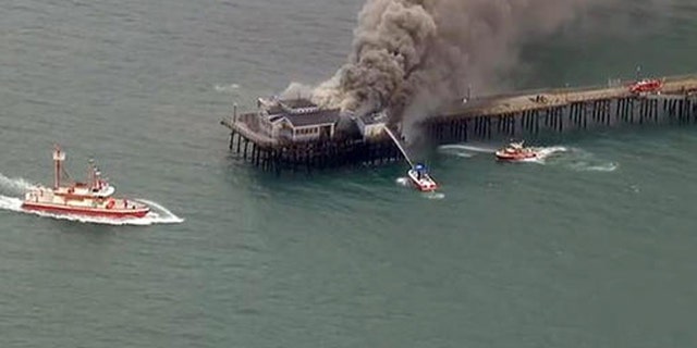 Firefighters attack a fire on the Seal Beach pier in Seal Beach, Calif. on Friday, May 20, 2016. (KABC-TV via AP)
