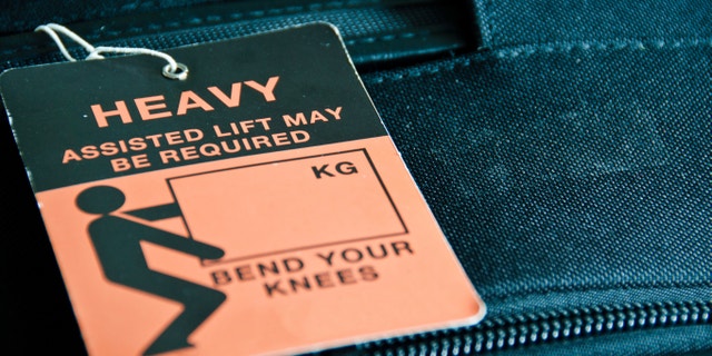 Luggage - black trolley - tagged with HEAVY sign
