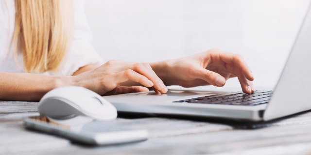 Close up of a woman's hand on a laptop keyboard.