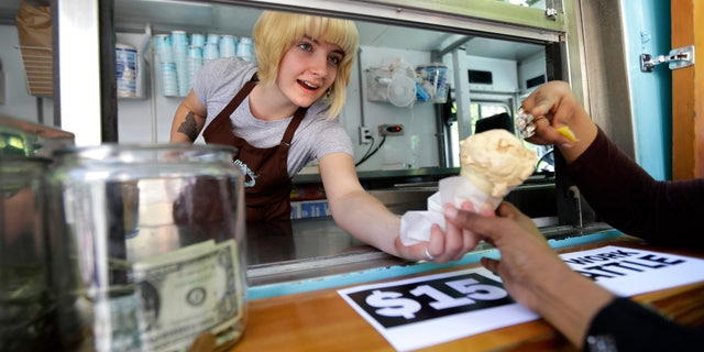 June 2, 2014: Caitlyn Faircloth, a worker with Molly Moon's Homemade Ice Cream, hands out free ice cream next to a tip jar at a rally celebrating the passage of a $15 minimum wage measure outside Seattle City Hall in Seattle.