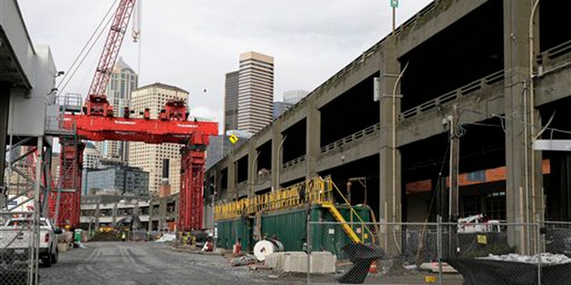 A crane is shown Friday, Dec. 18, 2015, at the site in Seattle, where an access pit had been dug to repair "Bertha," the massive tunnel boring machine digging a replacement for the Alaskan Way Viaduct elevated roadway, after it hit an underground pipe more than two years ago. Officials have said that the machine could resume tunneling as early as next week. (AP Photo/Ted S. Warren)