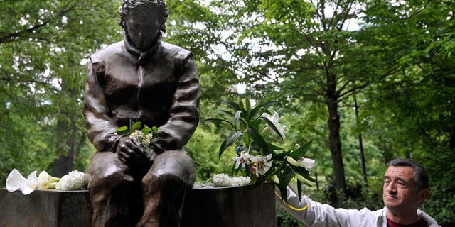 A man lays flowers next to a statue of Ayrton Senna, in a park close to the Imola track, Italy, Wednesday, April 30, 2014. It is a testament to Ayrton Senna's lasting impact on Formula One that the 20th anniversary of his death will be observed this week with five days of commemorations at the Imola track where he had his fatal accident. Current and past F1 drivers, mechanics, racing officials and fans will pay their respects to Senna and Austrian driver Roland Ratzenberger, who also died at the 1994 San Marino Grand Prix. (AP Photo/Marco Vasini)