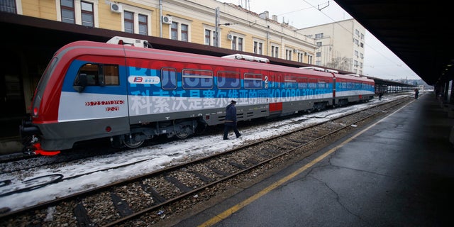 A railroad worker walks by a train decorated with letters that read "Kosovo is Serbian."