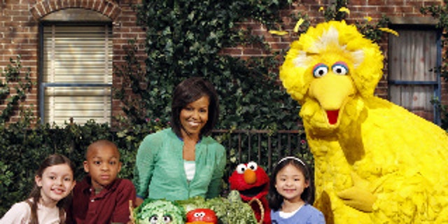 This May 5, 2009 photo released by Sesame Workshop shows first lady Michelle Obama, third from left, with Big Bird, Elmo, Muppets &amp; cast in "Michelle Obama Plants A Garden" in Astoria, N.Y. Mrs. Obama appears on "Sesame Street" Tuesday, Nov. 10, 2009, and recently taped an episode of "Iron Chef America," just two of the varied platforms she's been using lately to get her healthy-eating message out to the masses. (AP Photo/Sesame Workshop, Richard Termine)