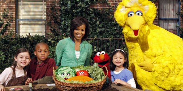 This May 5, 2009 photo released by Sesame Workshop shows first lady Michelle Obama, third from left, with Big Bird, Elmo, Muppets & cast in "Michelle Obama Plants A Garden" in Astoria, N.Y. Mrs. Obama appears on "Sesame Street" Tuesday, Nov. 10, 2009, and recently taped an episode of "Iron Chef America," just two of the varied platforms she's been using lately to get her healthy-eating message out to the masses. (AP Photo/Sesame Workshop, Richard Termine)