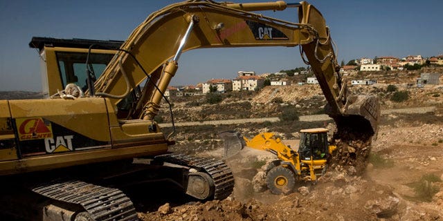 FILE: This Sept. 28, 2010, photo shows workers using ground moving equipment at a construction site in the Jewish settlement of Revava, near the West Bank city of Nablus.