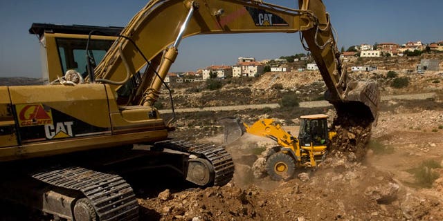FILE: This Sept. 28, 2010, photo shows workers using ground moving equipment at a construction site in the Jewish settlement of Revava, near the West Bank city of Nablus.