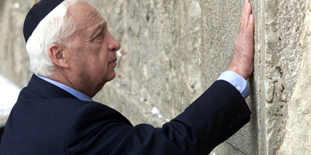 Former Israeli Prime Minister Ariel Sharon touches the stones of the Western Wall, also known as the Wailing Wall, as he prays while visiting the Old City Feb, 7, 2001, the morning after being elected as Israel's 39th next prime minister. Sharon as opposition leader visited the Temple Mount which led to violence among Palestinians and Israelis.