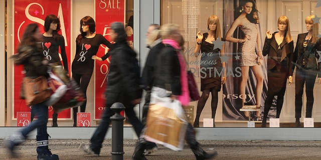 BERLIN, GERMANY - DECEMBER 17: People walk by a clothing store adevertising sales on a shopping street in Steglitz district on December 17, 2012 in Berlin, Germany. Retailers are hoping for a strong Christmas season in Germany, one of the few countries whose economy has so far weathered the current Eurozone debt crisis relatively well. (Photo by Sean Gallup/Getty Images)