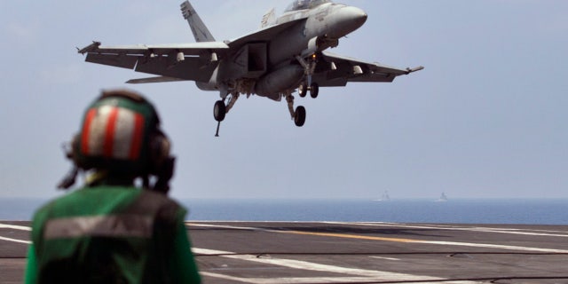 FILE - This Oct. 17, 2015 file photo shows a U.S. Navy fighter jet approaching to land on the U.S. Navy aircraft carrier USS Theodore Roosevelt during Exercise Malabar 2015 about 150 miles off Chennai, India. (AP Photo/Arun Sankar K., File)