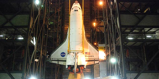 Space shuttle Discovery is hoisted into position to be attached to its external tank and solid rocket boosters for its final launch into space on the STS-133 mission to the International Space Station.
