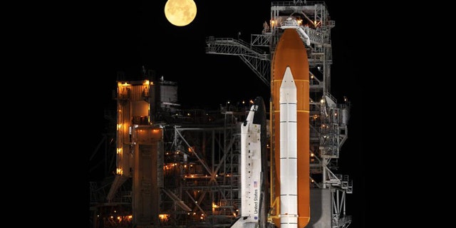 The space shuttle Discovery stands ready for liftoff at Launch Pad 39A at NASA's Kennedy Space Center in Cape Canaveral, Fla. Behind the shuttle, a nearly full moon sets. Discovery is poised to launch on the STS-119 mission in March 2009.