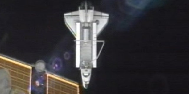 July 19: A photo made from NASA television shows the Atlantis as it passes under a solar panel on the Internatoinal Space Station after undocking.