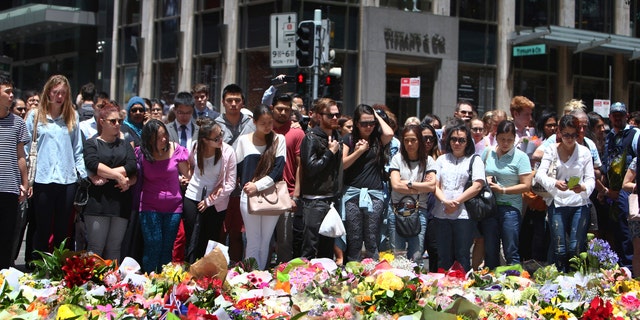 Dec. 16, 2014: Staff members from the Lindt Chocolat Cafe with their arms linked pay tribute to their colleague who lost his live during a siege at the popular coffee shop at Martin Place in the central business district of Sydney, Australia.