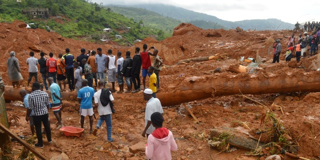 Residents stand as rescue workers search for survivors after a mudslide in the mountain town of Regent, Sierra Leone August 14, 2017.