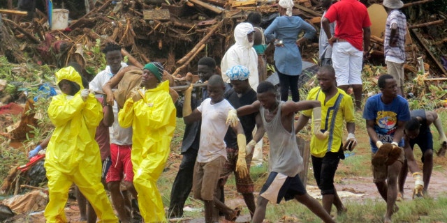 Rescue workers carry the body of a victim from the site of a mudslide in Regent, east of Freetown, Sierra Leone, Monday, Aug. 14, 2017.