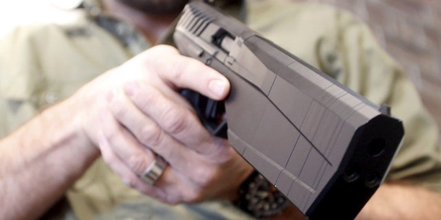 FILE: Feb. 23, 2016: SilencerCo CEO Joshua Waldron cradles a handgun with a built-in suppressor. West Valley City, Utah. (Reuters)