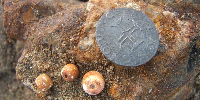 A coin and rosary beads discovered in the Namibian shipwreck (Dieter Noli).