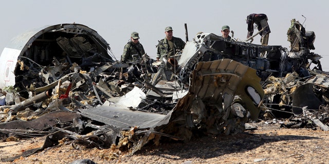 Nov. 1, 2015: Military investigators from Russia stand near the debris of a Russian airliner at the site of its crash at the Hassana area in Arish city, north Egypt.