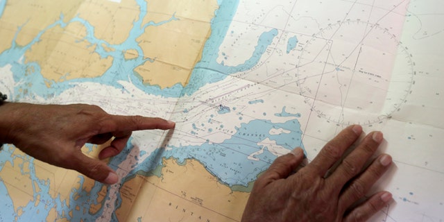 Tan Hua Chiow, a retired Singapore naval officer, shows a naval chart and explains to the Associated Press the flow of traffic at sea.