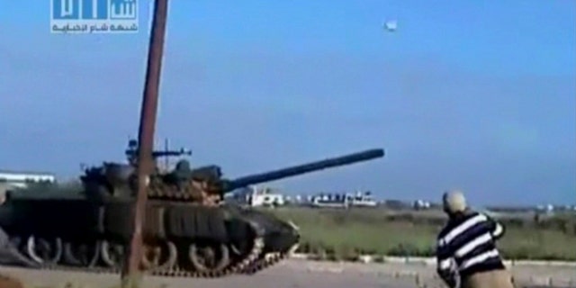 April 24: This video image taken from amateur video released by Sham News Network, a Syrian Freedom group, shows a man throwing an object at a tank in Daraa, Syria. (AP)