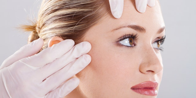 closeup of doctor conduct skin check before plastic surgery