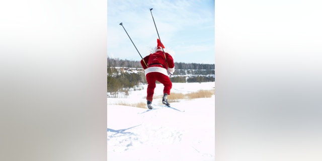 Rear view of Santa Claus jumping on skies