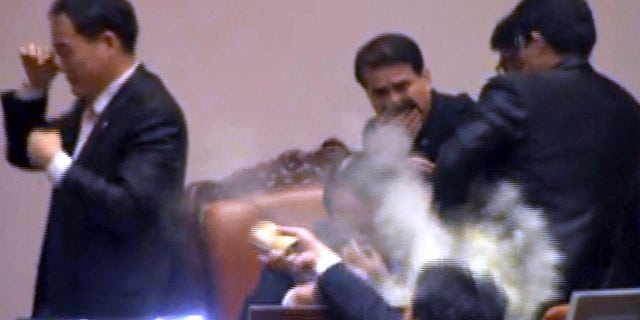 Nov. 22, 2011: Rep. Kim Seon-dong, bottom, of the opposition Democratic Labor Party, explodes tear gas in front of the speaker's chair to block National Assembly Vice Speaker Chung Eui-hwa, center, from pushing for the procedure to handle a pending bill on ratification of a South Korea-U.S. free trade agreement at the National Assembly in Seoul, South Korea.