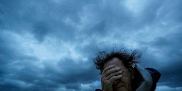Russ Lewis covers his eyes from a gust of wind and a blast of sand as Hurricane Florence approaches Myrtle Beach, S.C., Friday, Sept. 14, 2018.