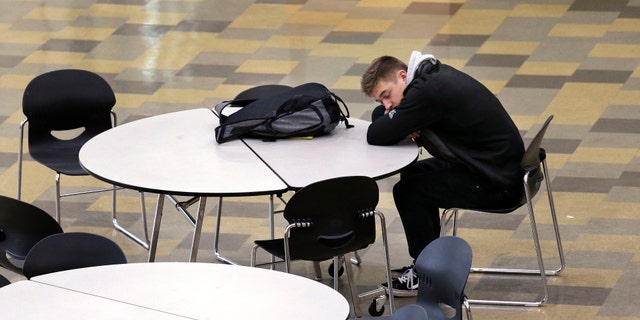 In this photo taken Nov. 23, 2015, a student leans on a table in the cafeteria during first period at Roosevelt High School in Seattle. More school districts around the U.S. are heeding the advice of scientists who have long said that expecting teens to show up to class before 8 a.m. isnt good for their health or their report cards. (AP Photo/Elaine Thompson)
