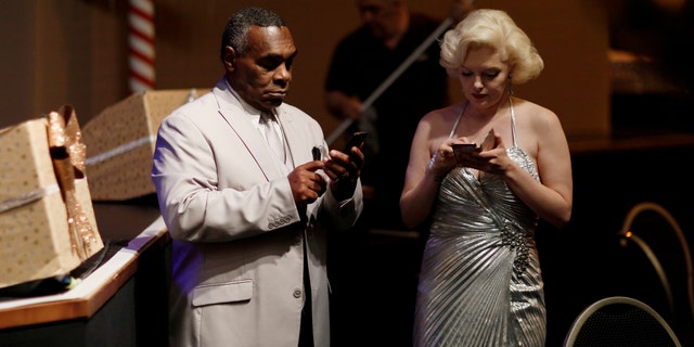 File photo: Performers dressed as Marilyn Monroe and Louis Armstrong check their smartphones before a "Stars in Concert" show at the Estrel hotel in Berlin, Germany, December 7, 2016. (REUTERS/Hannibal Hanschke)