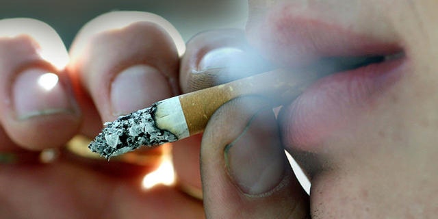 A person smokes outside his place of work in Belfast, Northern Ireland, Monday, April, 30, 2007. A smoking ban in all public places has come into effect from Monday in Northern Ireland. (AP Photo/Peter Morrison)