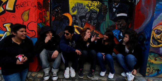 Teenagers smoke and talk in front of a vacant business in Ushuaia, Argentina. REUTERS/Jim Urquhart
