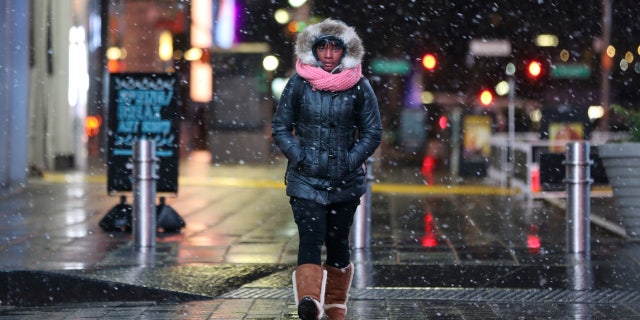 A woman walks as snow falls in Times Square in Manhattan in New York City, New York, U.S., March 7, 2018.