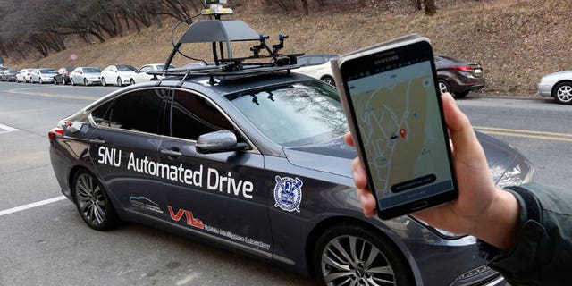 A researcher from the Intelligent Vehicle IT Research Center at Seoul National University shows the smartphone application for the driverless car called Snuber with a fixture on its roof with devices that scan road conditions.
