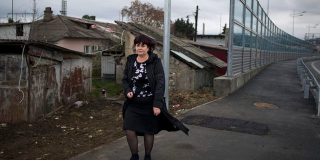 Nov. 27, 2013: Irina Kharchenko walks away from her house beside the screen separating the yard of her house and a federal highway in the village Vesyoloye outside Sochi, Russia. As the Winter Games are getting closer, many Sochi residents are complaining that their living conditions only got worse and that authorities are deaf to their grievances.
