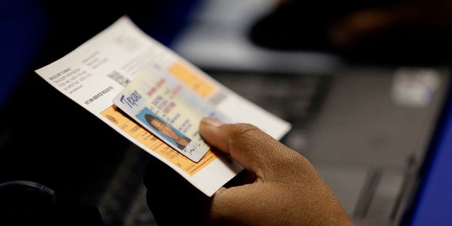 FILE - In this Feb. 26, 2014, file photo, an election official checks a voter's photo identification at an early voting polling site in Austin, Texas. A federal appeals court ruled Wednesday, July 20, 2016, that Texas' strict voter ID law discriminates against minorities and the poor and must quickly be scrubbed of those effects before the November 2016 election. Voters will still need to show identification at the polls under the decision by the New Orleans-based 5th U.S. Circuit Court of Appeals, according to attorneys who challenged the law, but a lower court will now also have to devise a way for Texas to accommodate those who cannot. (AP Photo/Eric Gay, File)