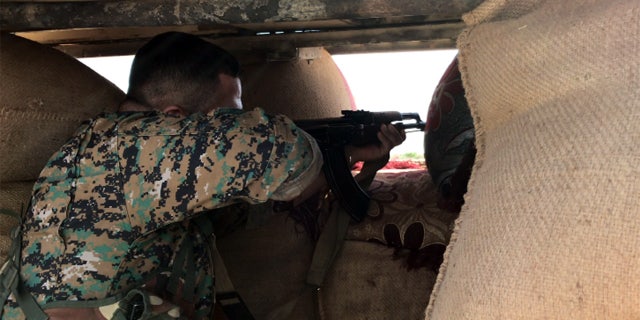 A soldier for the Syrian Democratic Forces at his post outside one of the remaining ISIS-held towns in Syria.