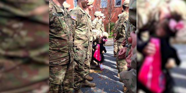 A young girl runs into the Savannah St. Patrick's Day parade to plant a kiss on a soldier.