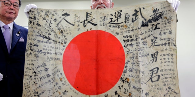 Strombo, right, holds the flag during a press conference in Tokyo.