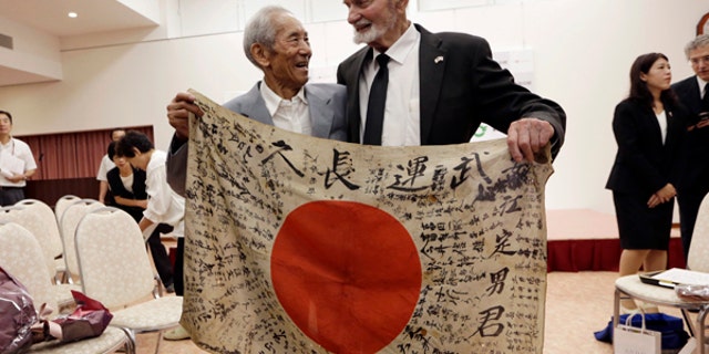 WWII veteran Marvin Strombo, right, and Tatsuya Yasue, 89-year-old farmer, hold a Japanese flag with autographed messages which was owned by his brother Sadao Yasue, who was killed in the Pacific during World War II. Strombo has returned to the fallen soldier's family the calligraphy-covered flag he took from the man's body 73 years ago.