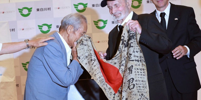 WWII veteran Marvin Strombo, center, returns Tatsuya Yasue, left, a Japanese flag with autographed messages which was owned by his brother Sadao Yasue, who was killed in the Pacific during World Work II, during a ceremony in Higashishirakawa.